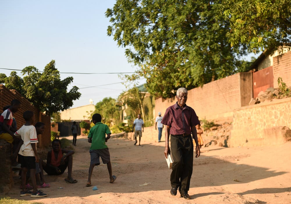 An older man walking home in Malawi with books to read