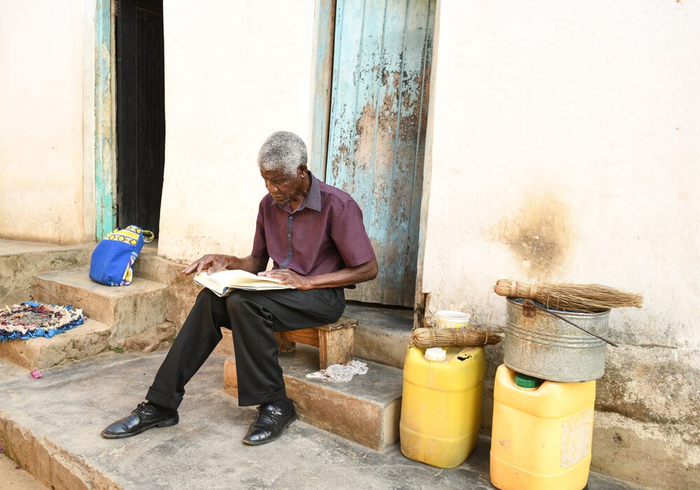 An older man reading books on his doorstep