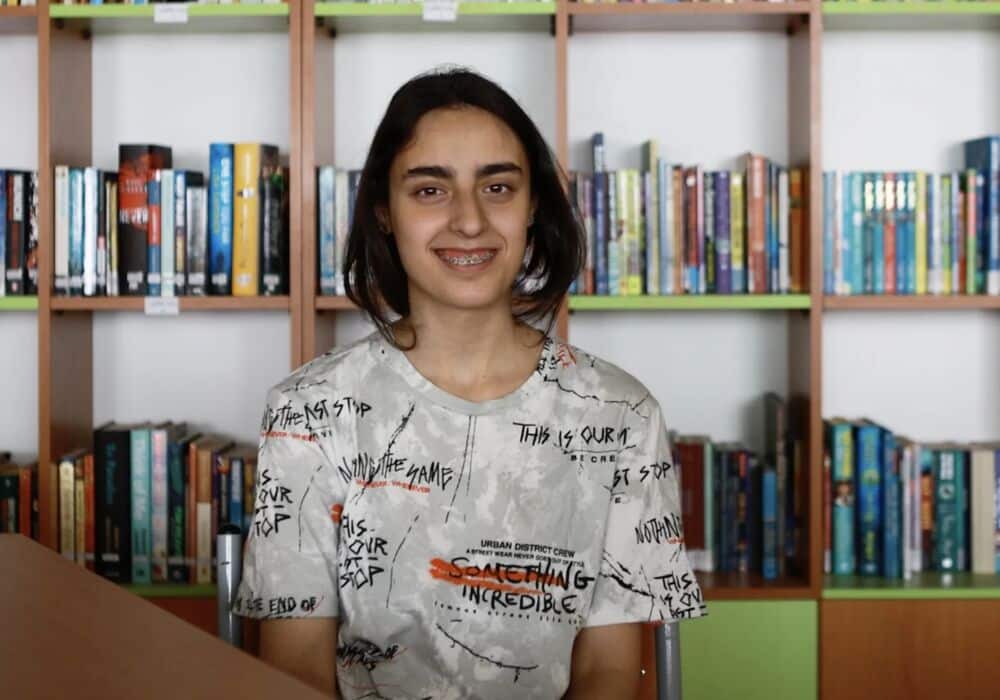 Maryam in front of shelves of books
